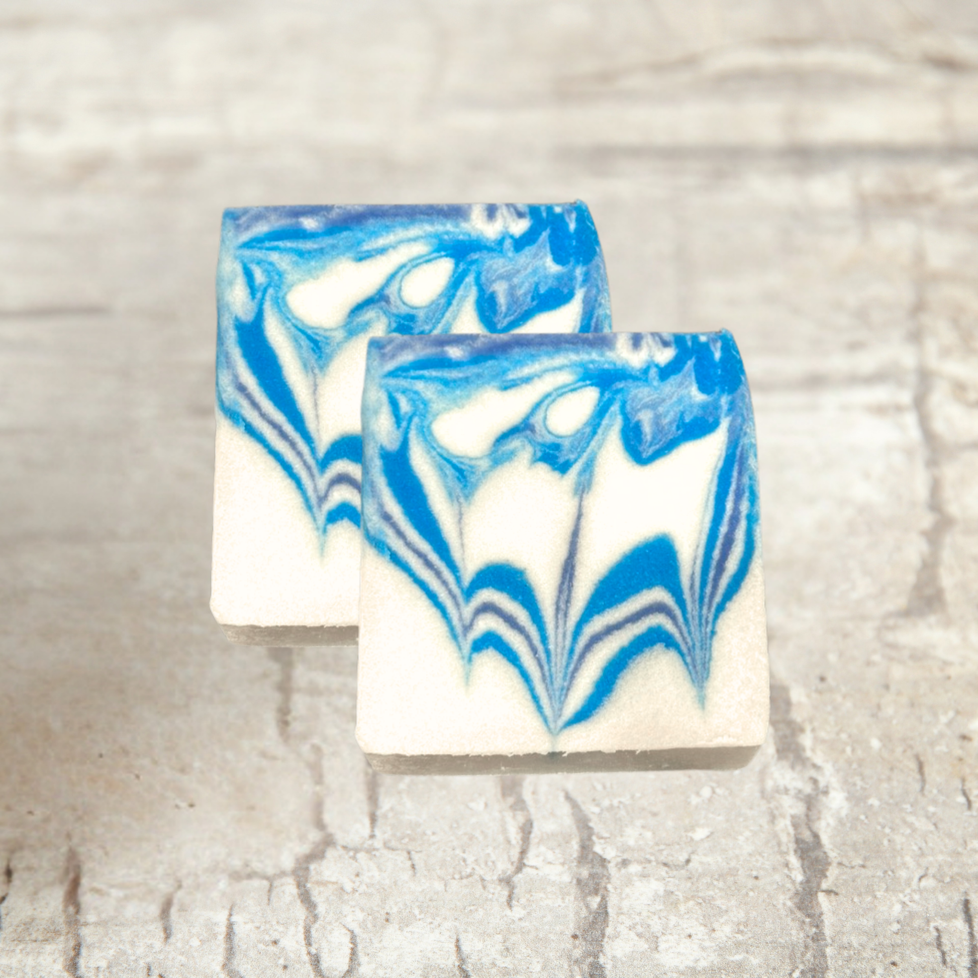 Two bars of soap with blue and white marbled pattern on a textured surface