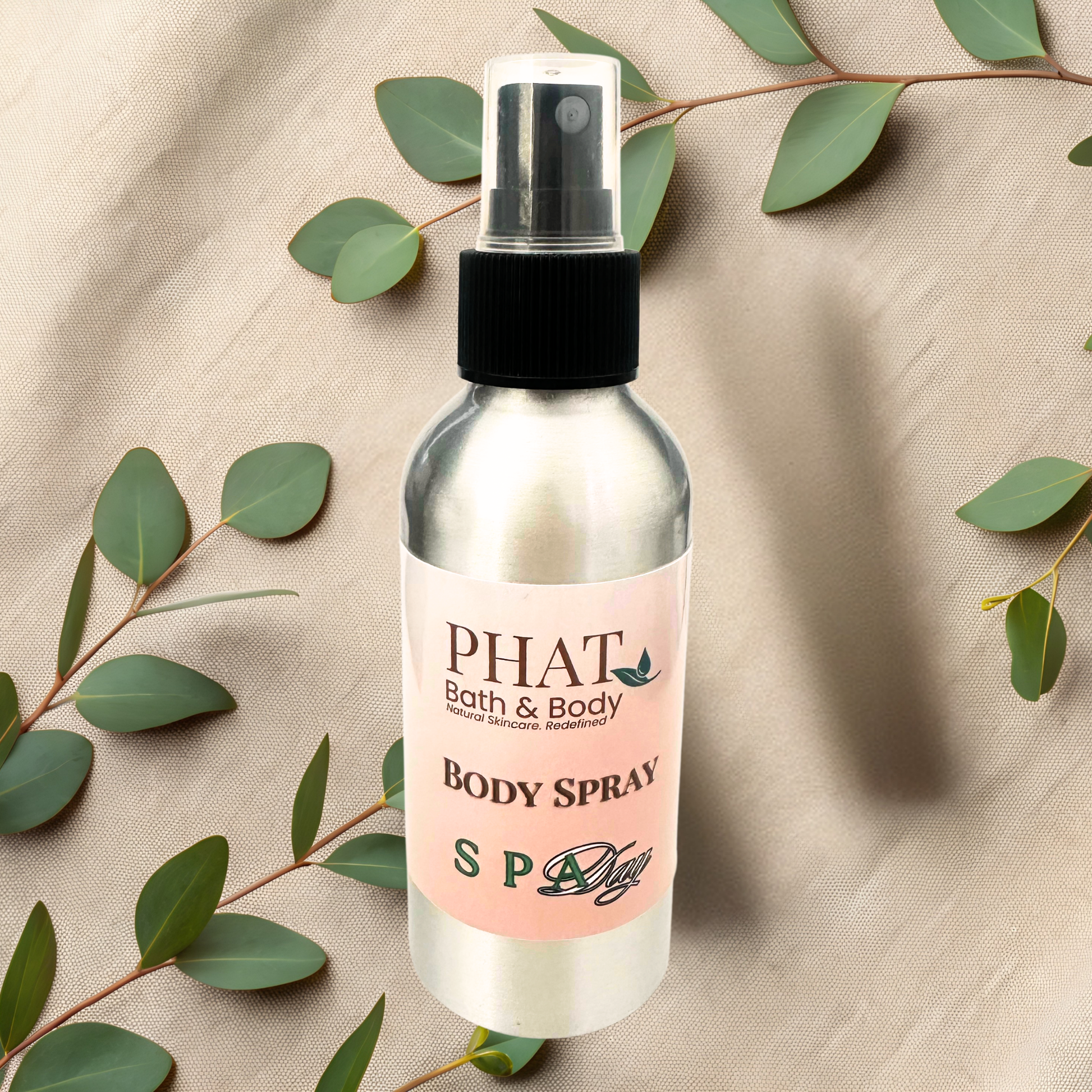 Body spray bottle with a pink label on a beige fabric background with green leaves.