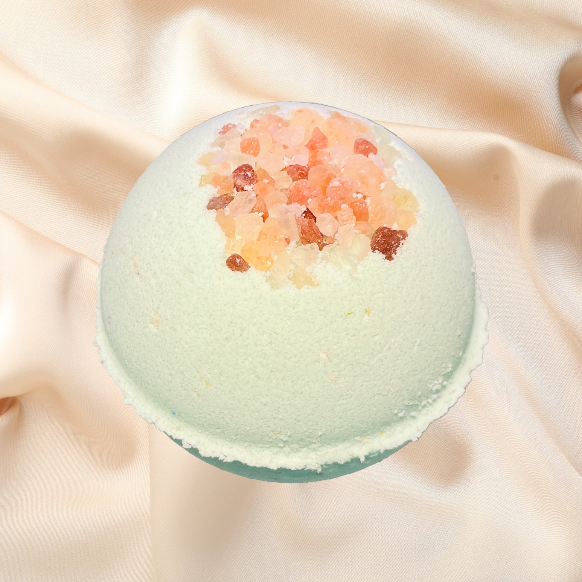 Green bath bomb with decorative elements on a beige fabric background