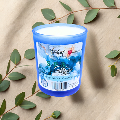 Blue candle with a label on a beige fabric background with green leaves