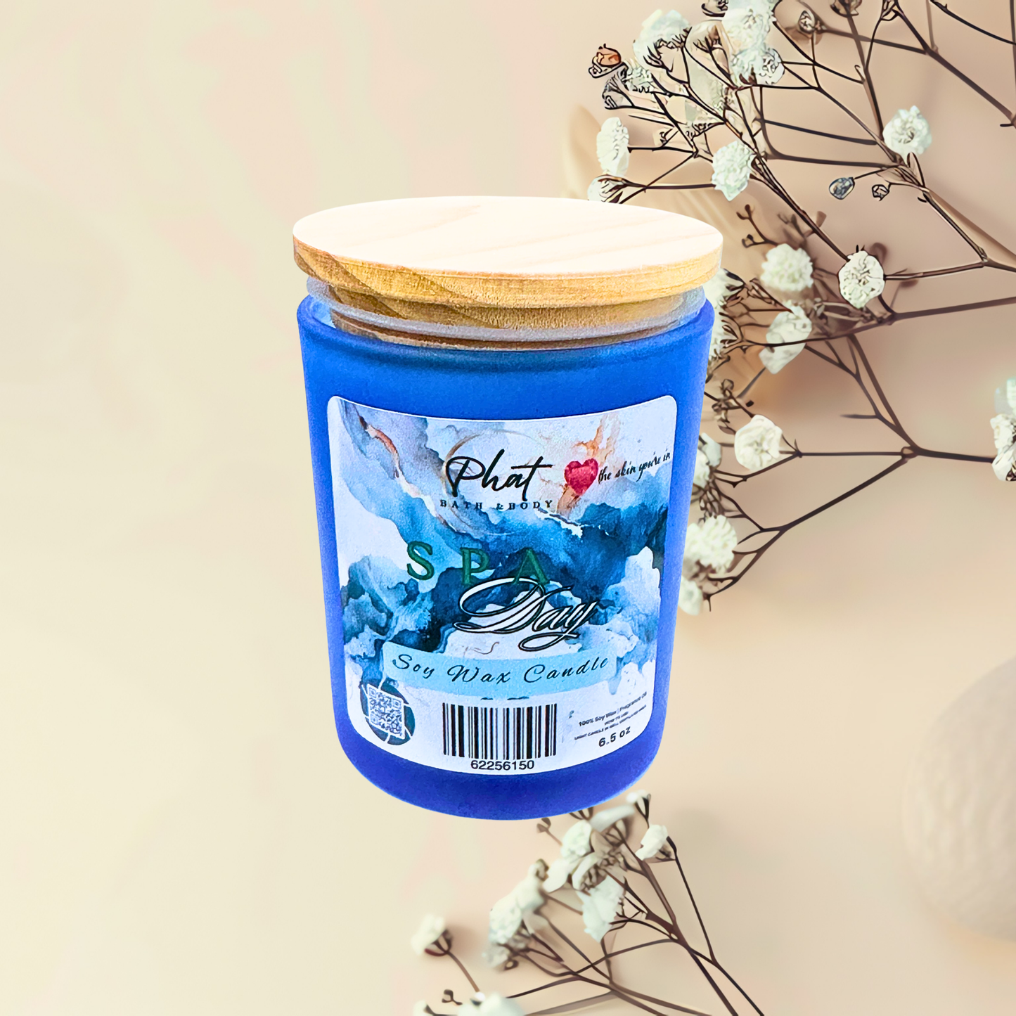 Blue candle with wooden lid on a beige background with white flowers