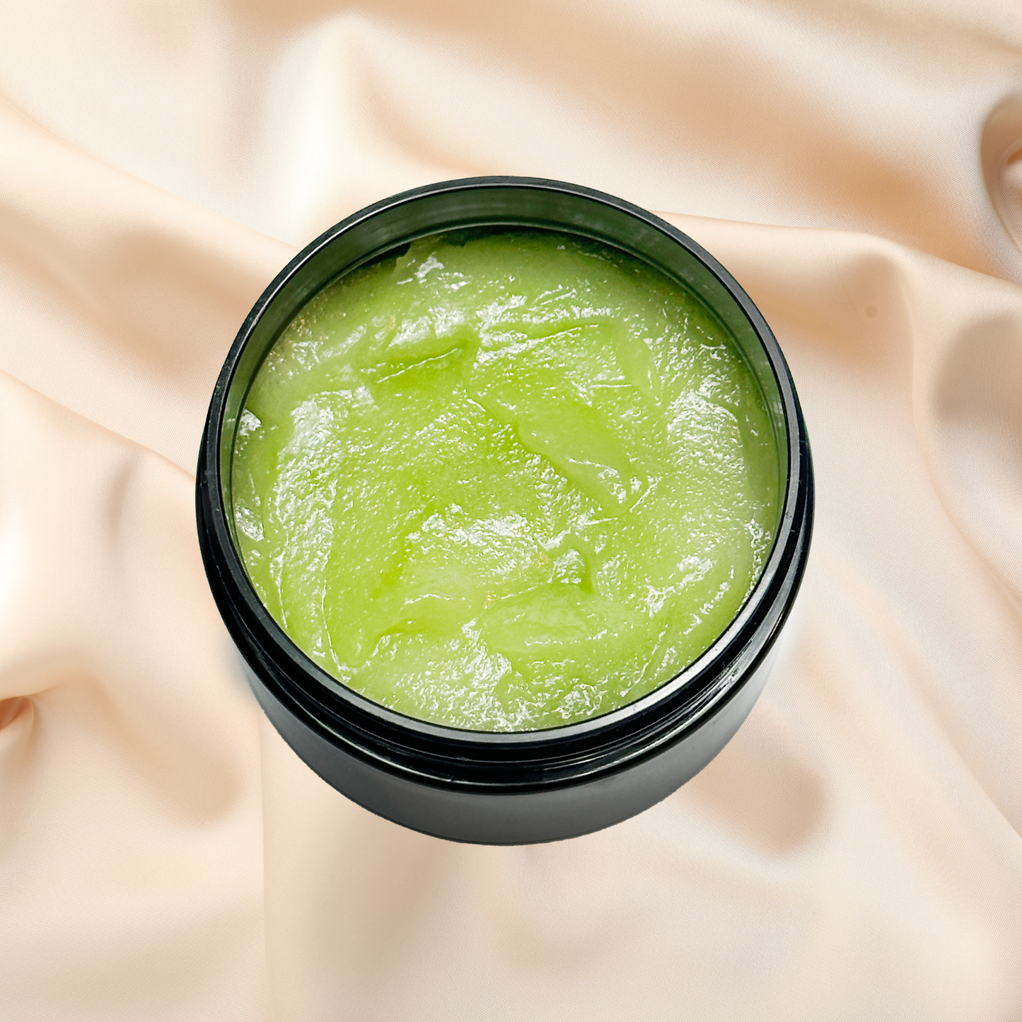 Green scrub in a black jar on a beige fabric background