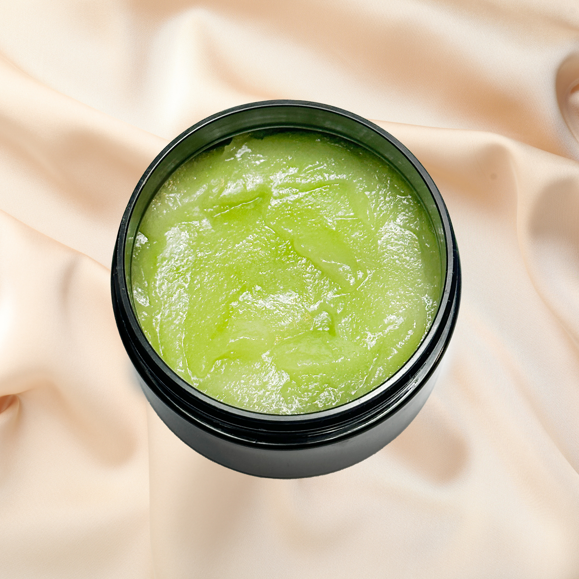 Green scrub in a black jar on a beige fabric background