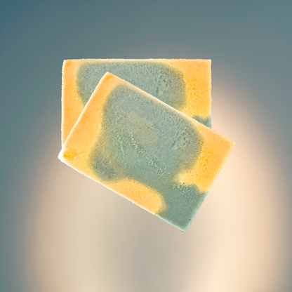 Two soaps with green and yellow coloration on a gradient background