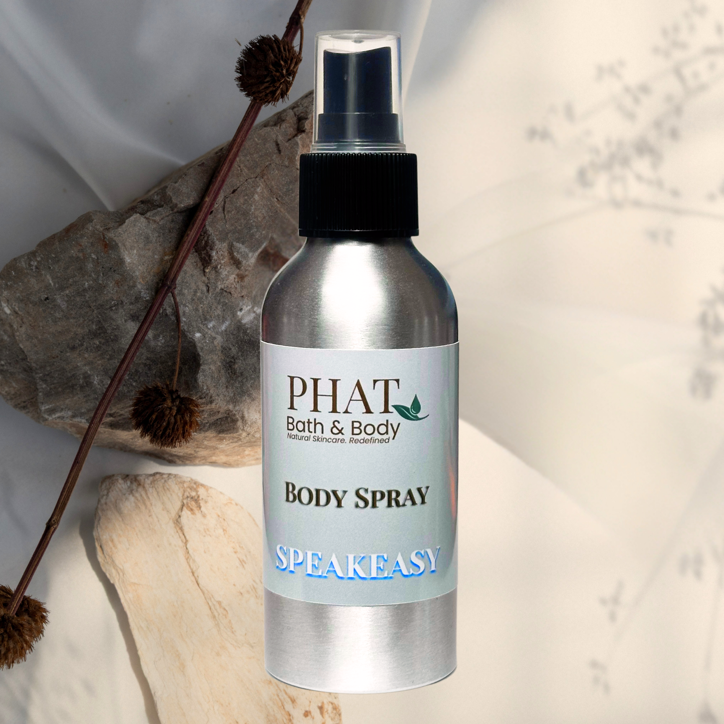 Body spray bottle labeled 'PHAT Bath & Body' on a natural stone background