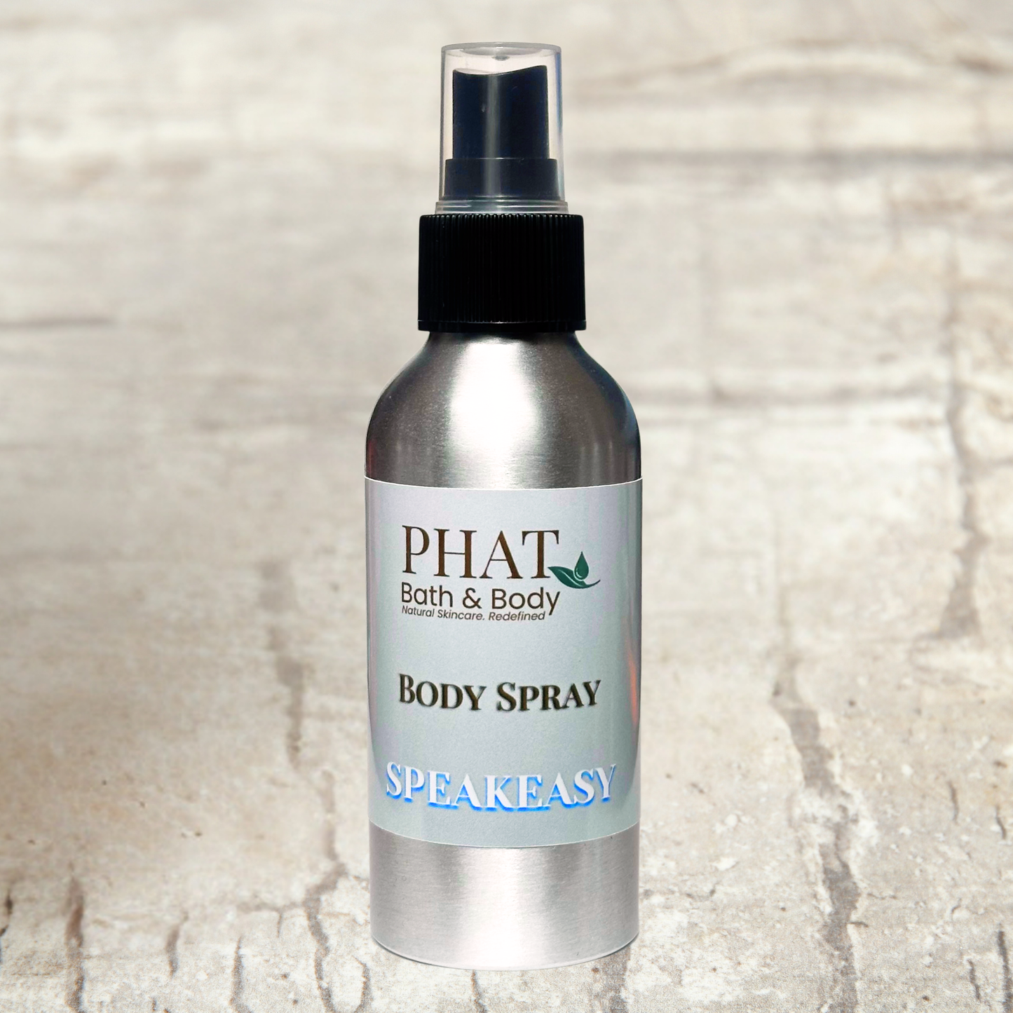 Body spray bottle labeled 'PHAT Bath & Body Speakeasy' on a textured beige background