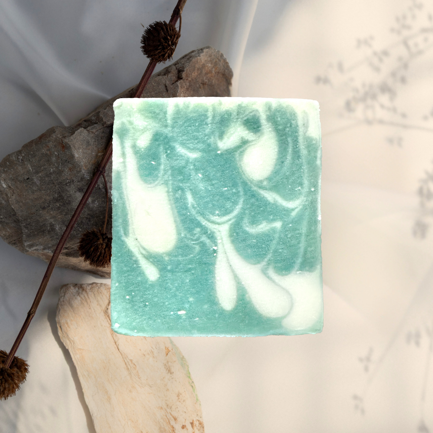 Green and white marbled soap bar on a stone surface with a natural background
