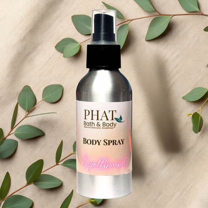 Body spray bottle with 'PHAT Bath & Body' label on a beige fabric background with green leaves.