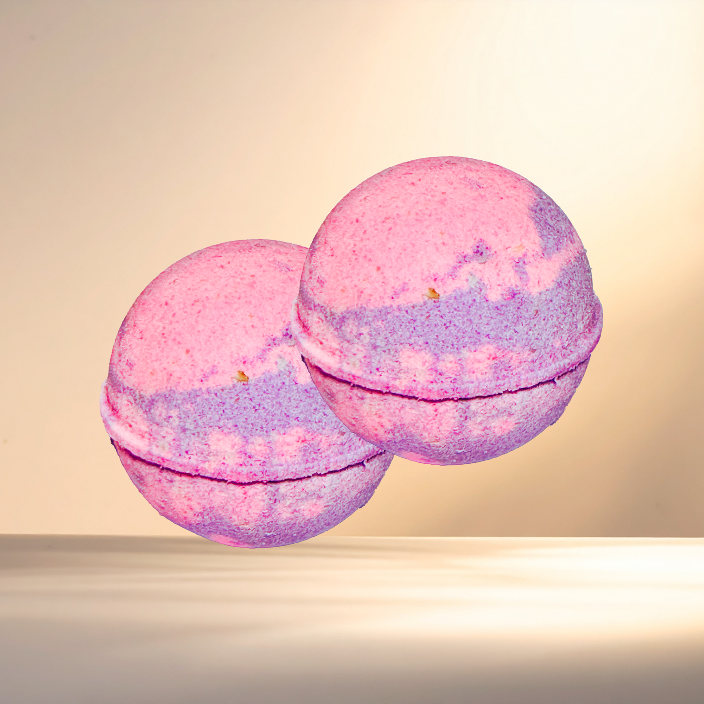 Two pink and purple bath bombs on a beige background