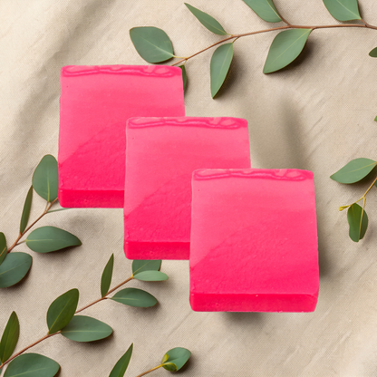 Three pink soap bars on a beige fabric background with green leaves.