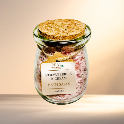 Jar of 'Strawberries & Cream' bath salts with a cork lid on a gradient background