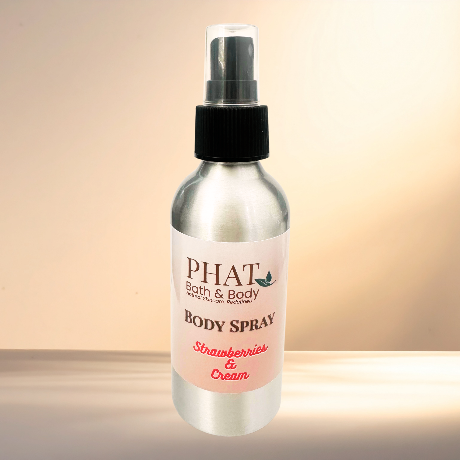 Body spray bottle labeled 'PHAT Bath & Body' with 'Strawberries & Cream' scent on a gradient background