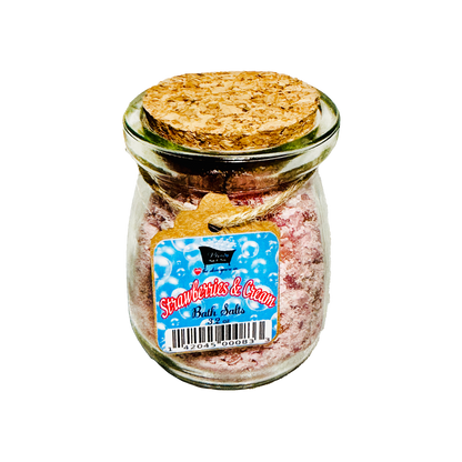 Jar of 'Strawberries & Cream' bath salts with a cork lid on a white background