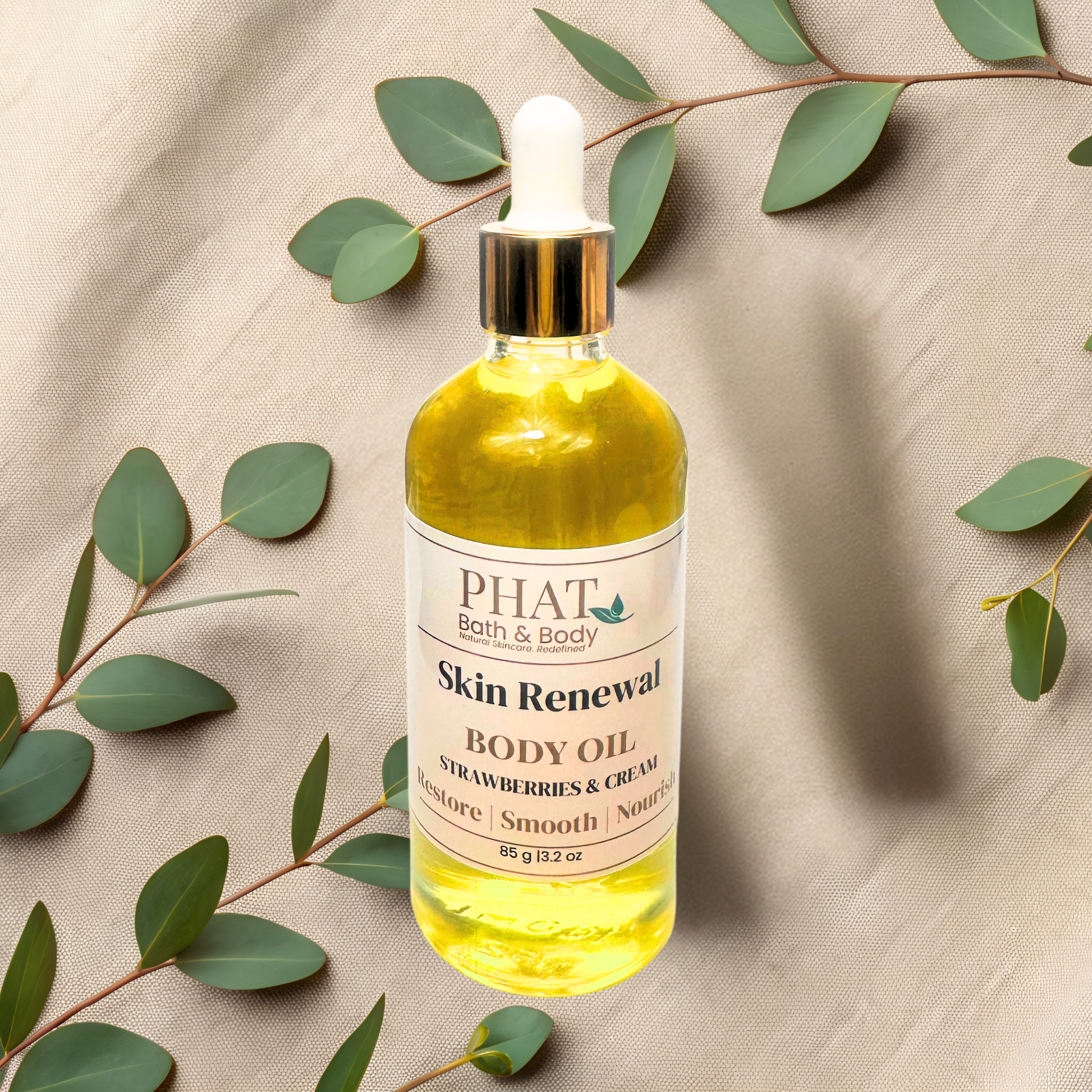 Bottle of PHAT Skin Renewal Body Oil with eucalyptus leaves on a beige fabric background