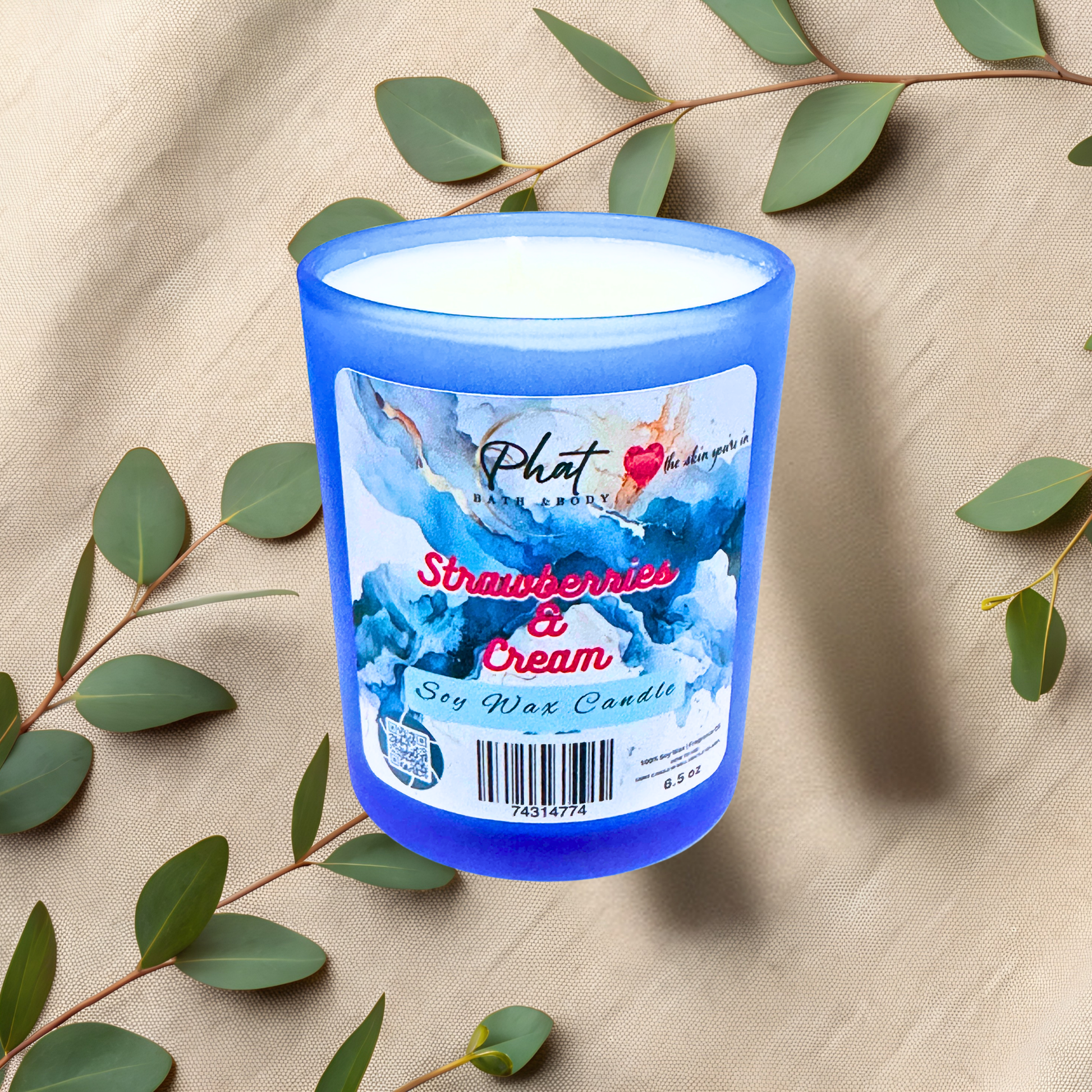 Blue candle with a label on a beige fabric background with green leaves