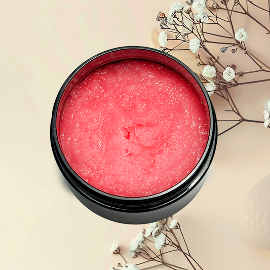 Pink sugar scrub in a black container with white flowers on a beige background
