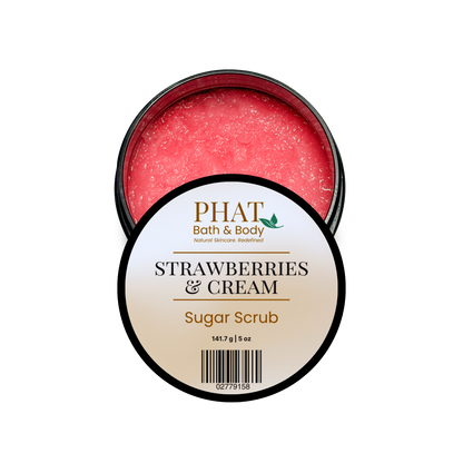 An open round tin of PHAT Bath & Body Strawberry & Cream Sugar Scrub, showing the pinkish-red scrub inside, with the white and gold label facing forward on a plain white background.