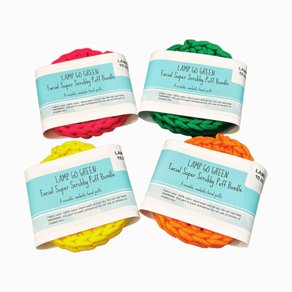 Four colorful facial scrubber puffs with labels on a dark red background