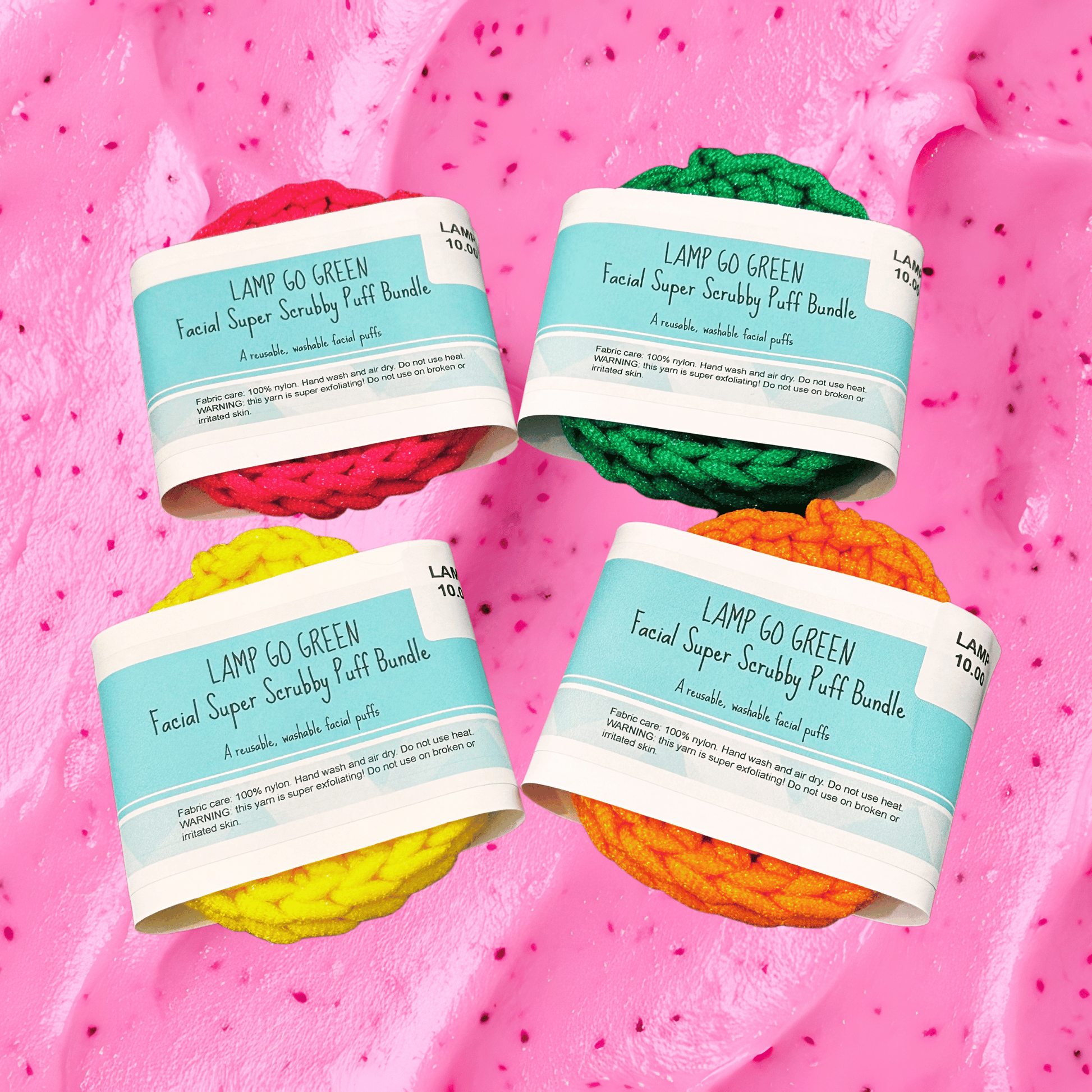 Four colorful facial scrubbies with labels on a pink textured background