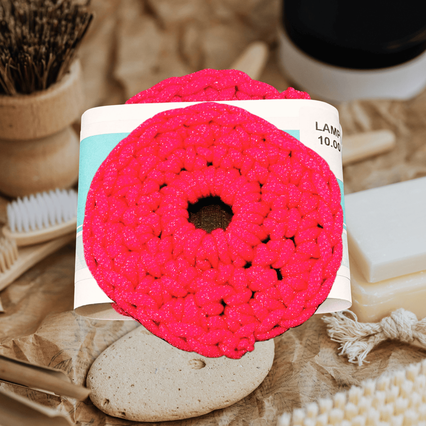 Pink crochet scrubbie on a card with natural items in the background
