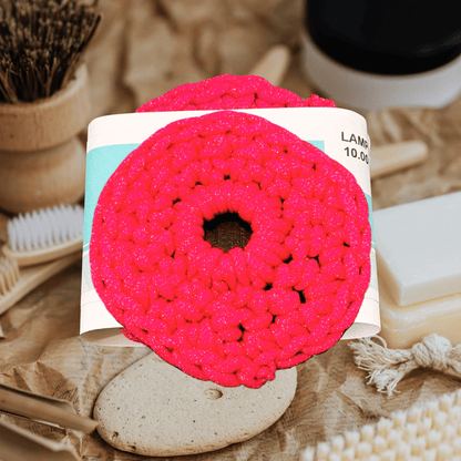 Pink crochet scrubbie on a card with natural items in the background