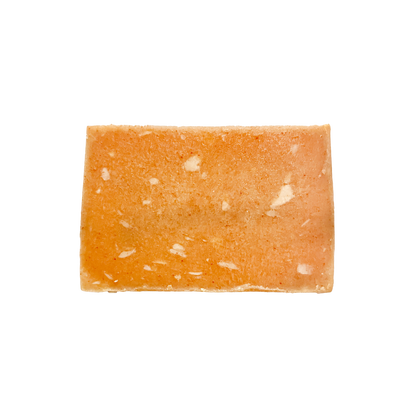 Rectangular piece of orange-colored soap with white specks on a white background