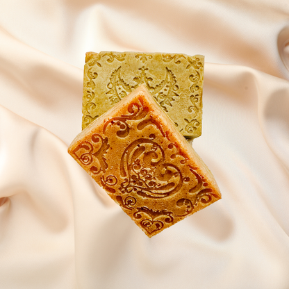 Two soap bars with intricate designs on a soft fabric background