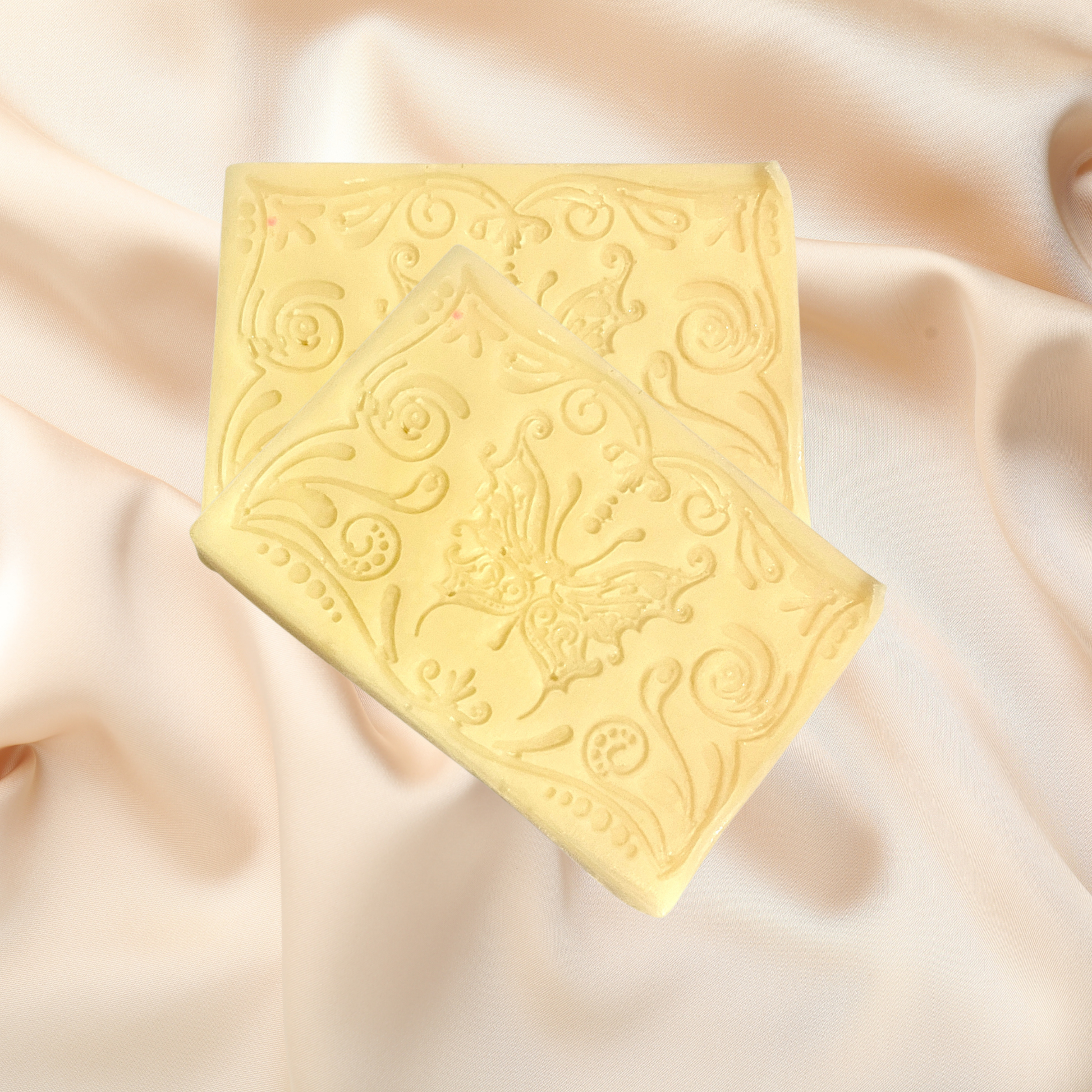 Decorative white soap bar with intricate patterns on a soft beige fabric background