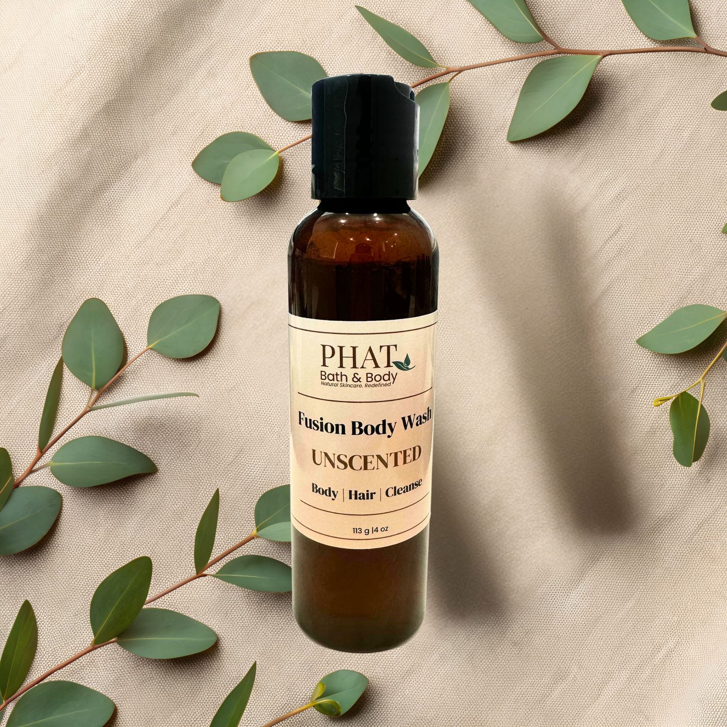 Bottle of PHAT Bath & Body Unscented body wash with green leaves on a beige fabric background
