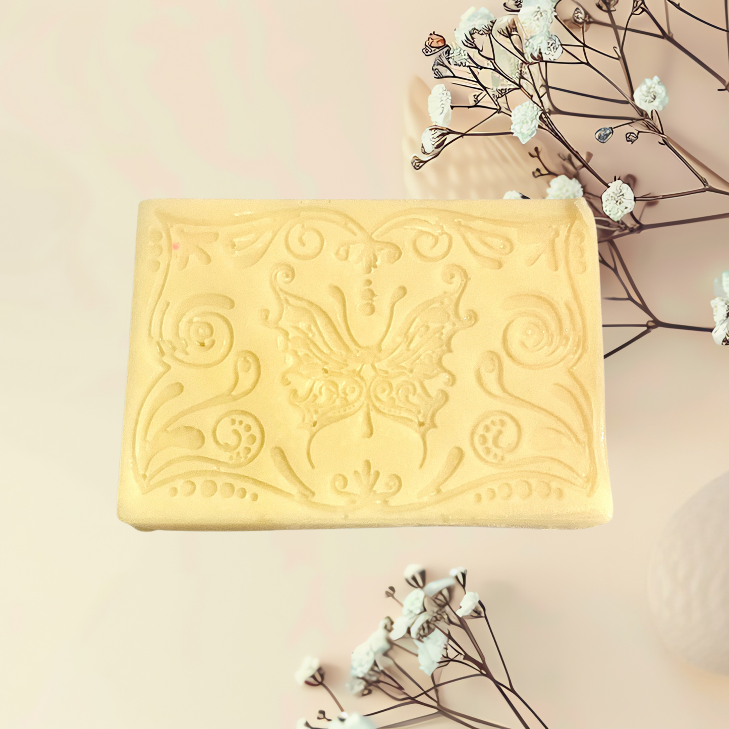 Decorative white soap bar with butterfly design on a light pink background with white flowers.