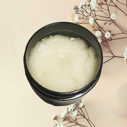 Black container with white scrub on a beige background with white flowers.