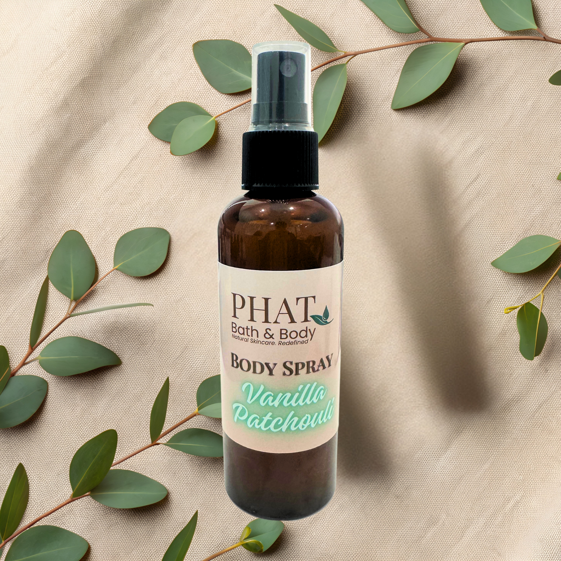 Bottle of 'Vanilla Patchouli' body product by PHAT Bath & Body on a beige fabric background with green leaves.
