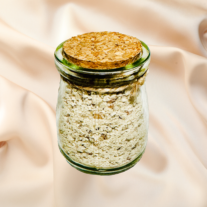 Glass jar with cork lid containing a light-colored bath salts on a beige fabric background