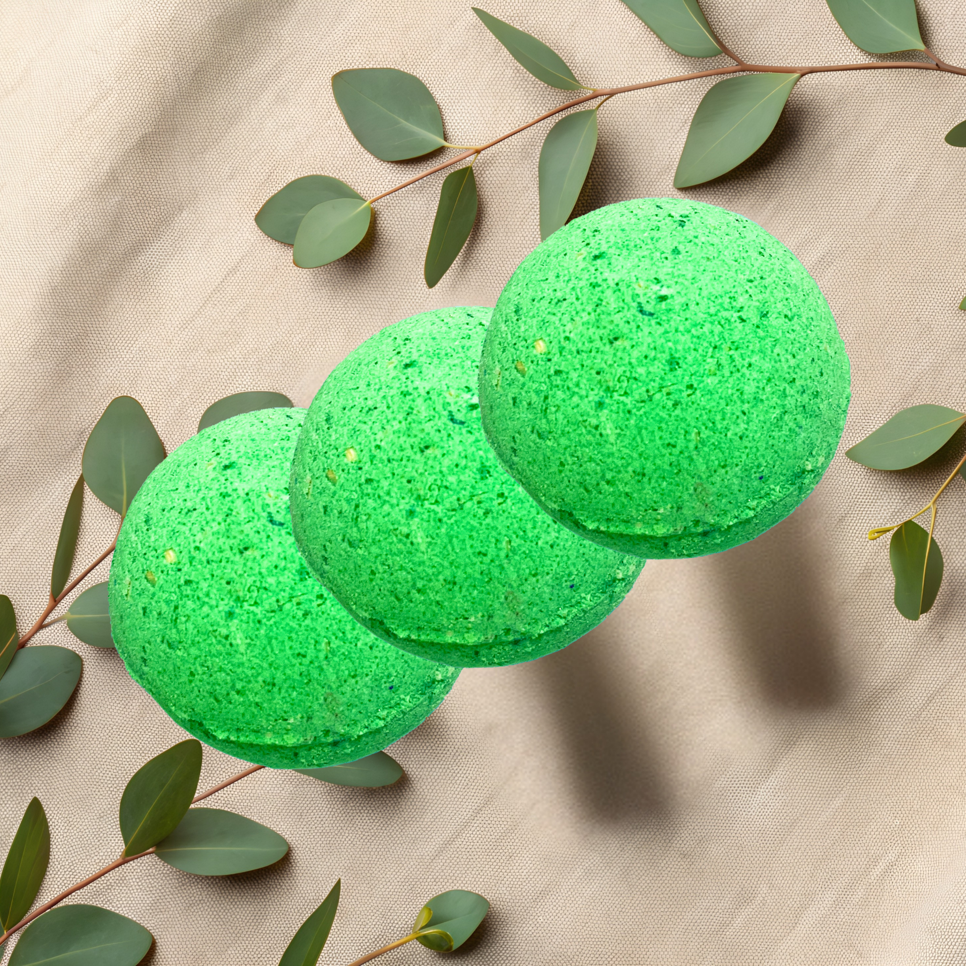 Three green bath bombs with eucalyptus leaves on a beige fabric background