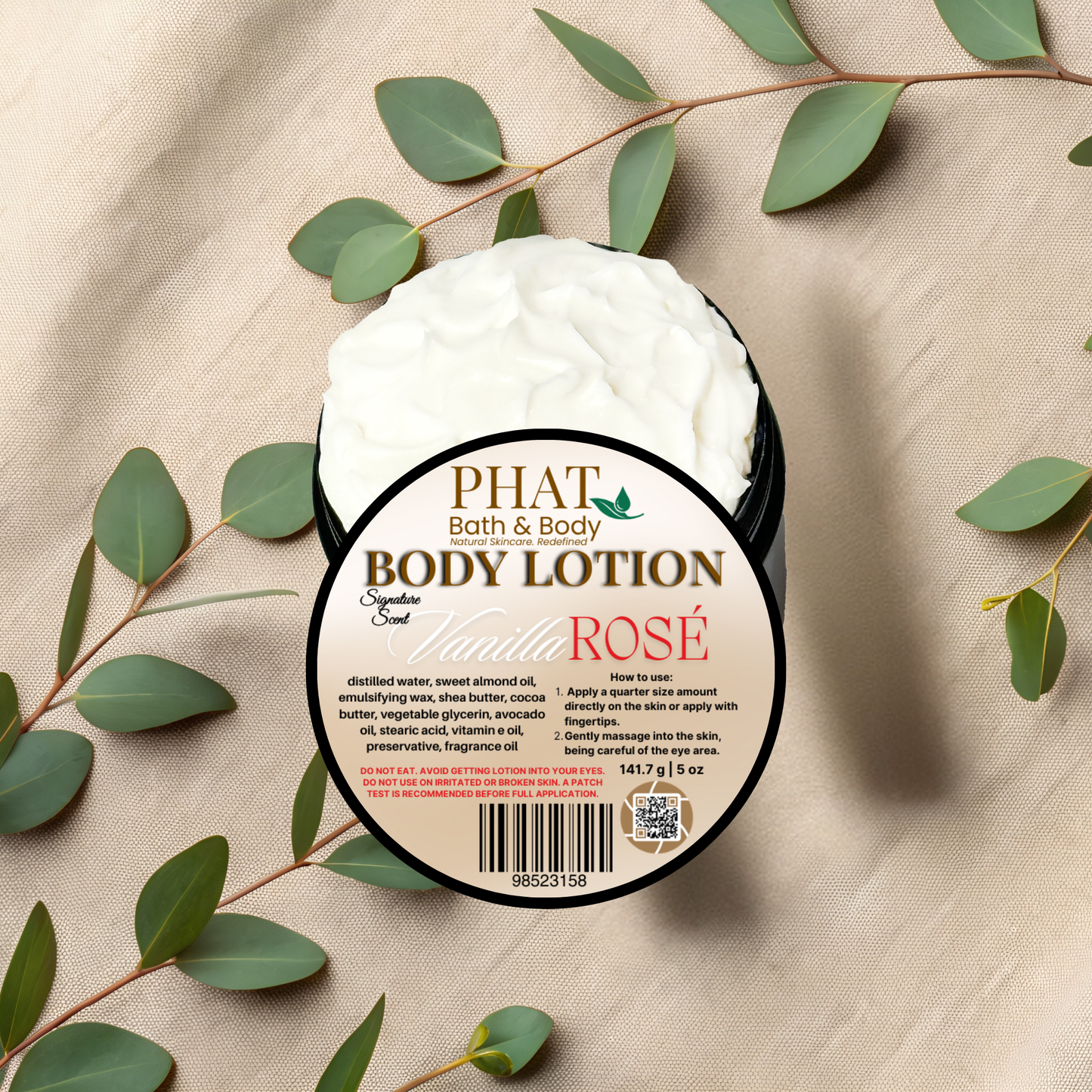 Body lotion container labeled 'PHAT Bath & Body' with 'Vanilla Rosé' on a beige fabric background with green leaves.