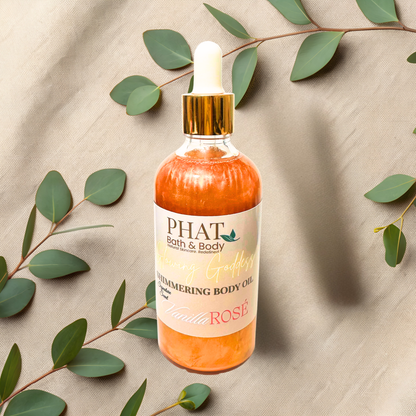 Bottle of 'PHAT Bath & Body' shimmering body oil with green leaves on a beige fabric background