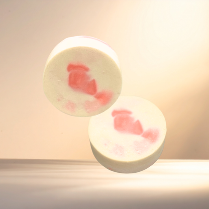 Two round, white soaps with red floral patterns on a light background