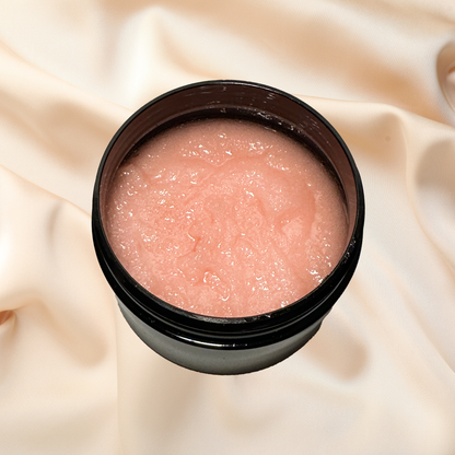 Pink sugar scrub in a black container on a beige fabric background