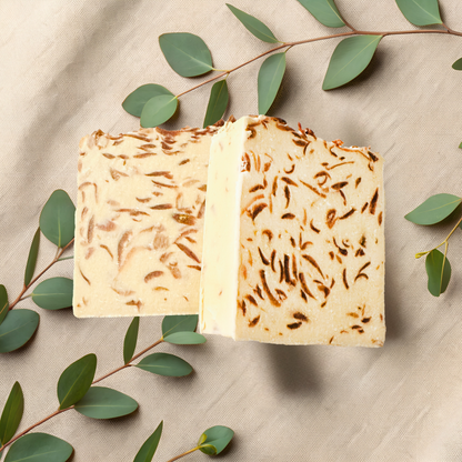 Two pieces of textured soap with green leaves on a beige fabric background
