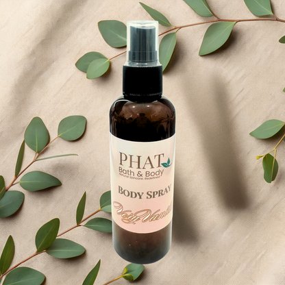 Body spray bottle with 'PHAT Bath & Body' label on a beige fabric background with green leaves.