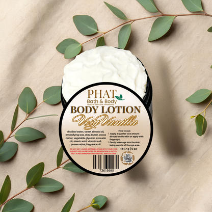 Body lotion container labeled 'PHAT Bath & Body' with vanilla scent on a beige fabric background with green leaves.