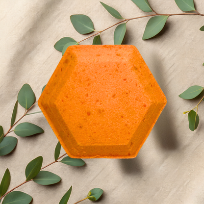 Hexagonal orange steamer on a beige fabric background with green leaves