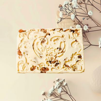 Decorative soap bar with intricate designs on a light background with flowers.