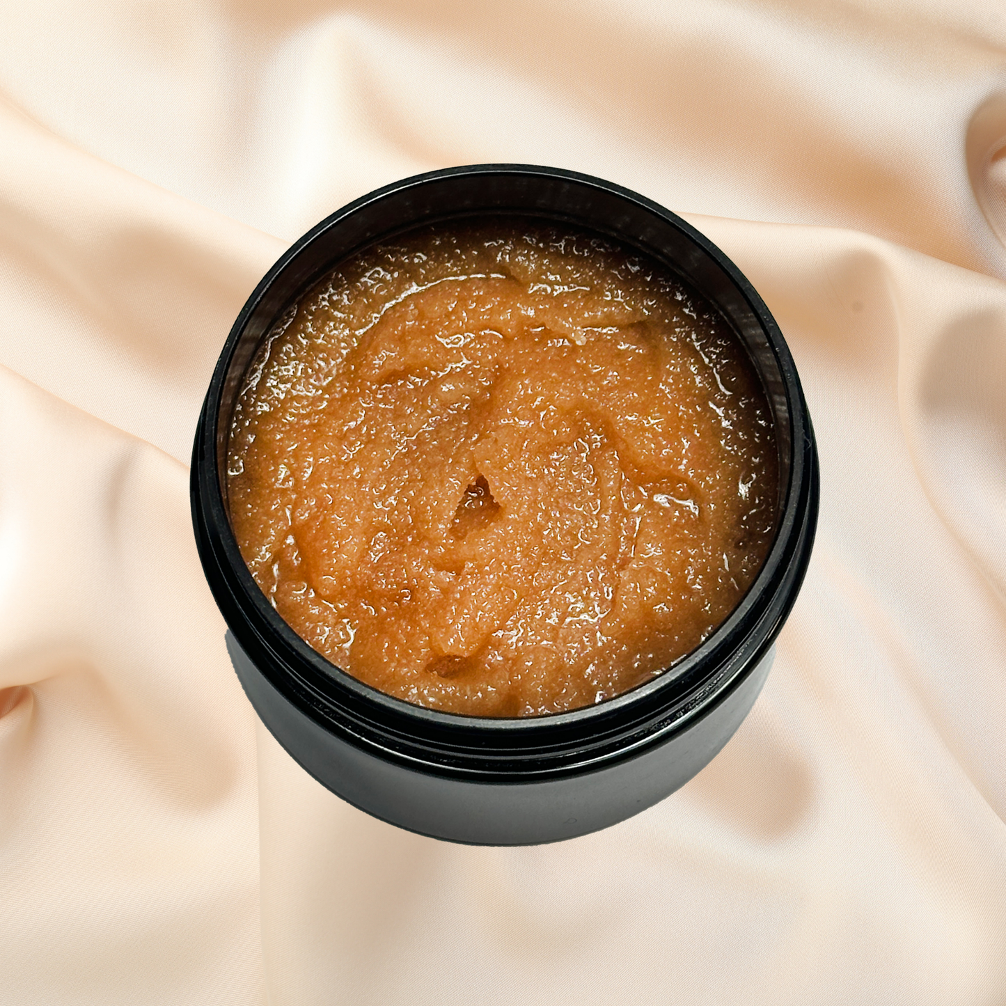 Black container of brown scrub on a beige fabric background