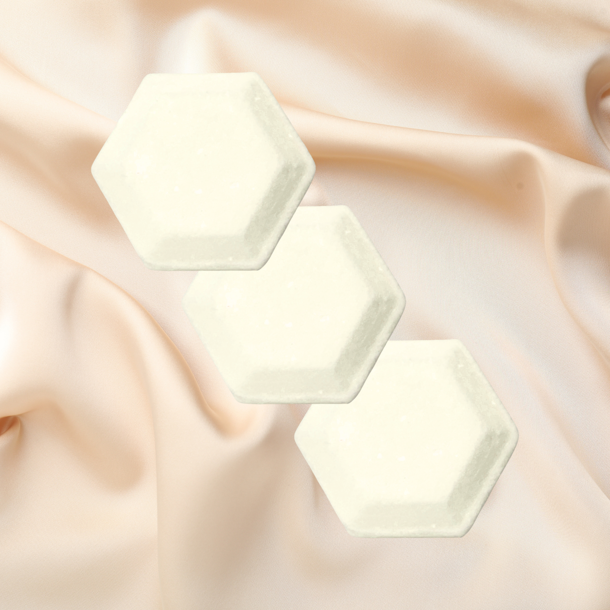 Three hexagonal shower bombs on a soft, draped fabric background