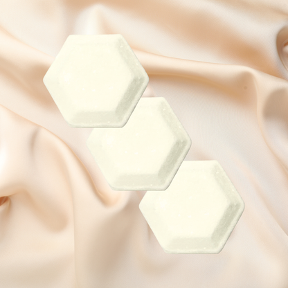 Three hexagonal shower bombs on a soft, draped fabric background