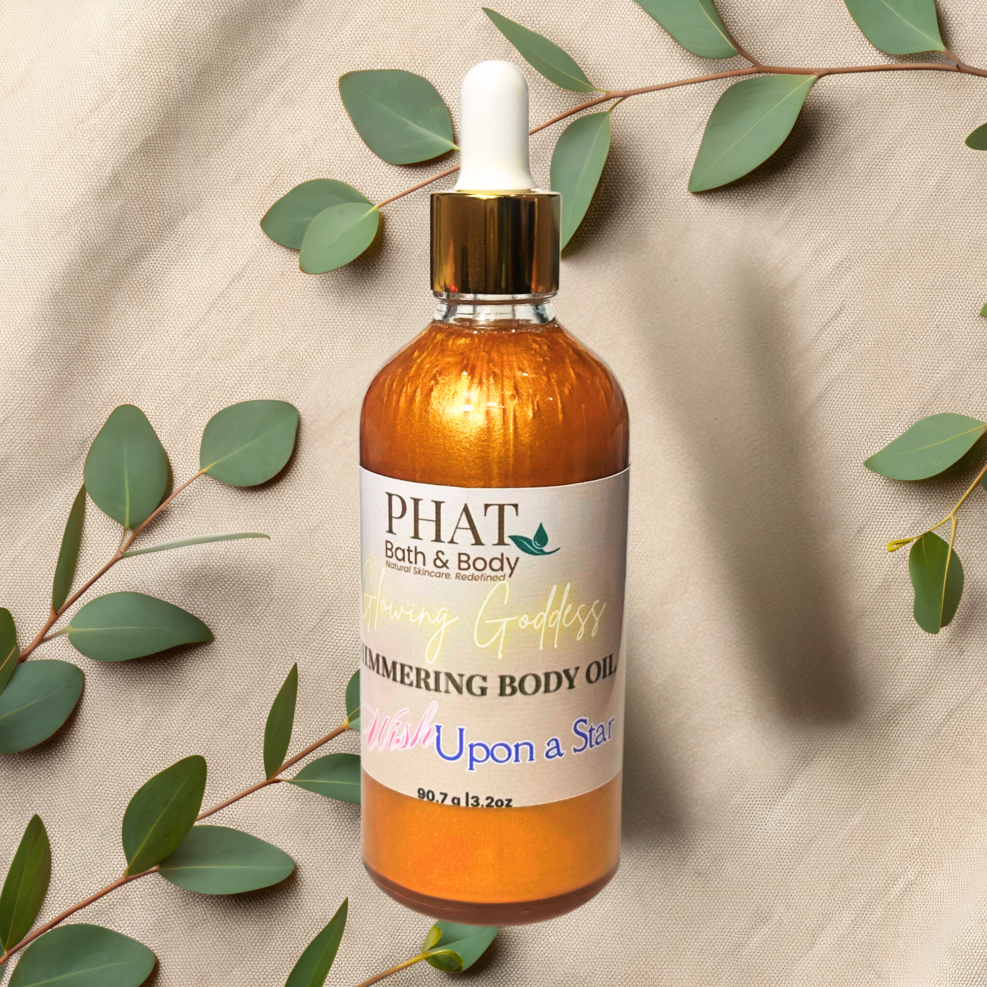 Bottle of PHAT Bath & Body body oil with a dropper on a beige fabric background with green leaves.