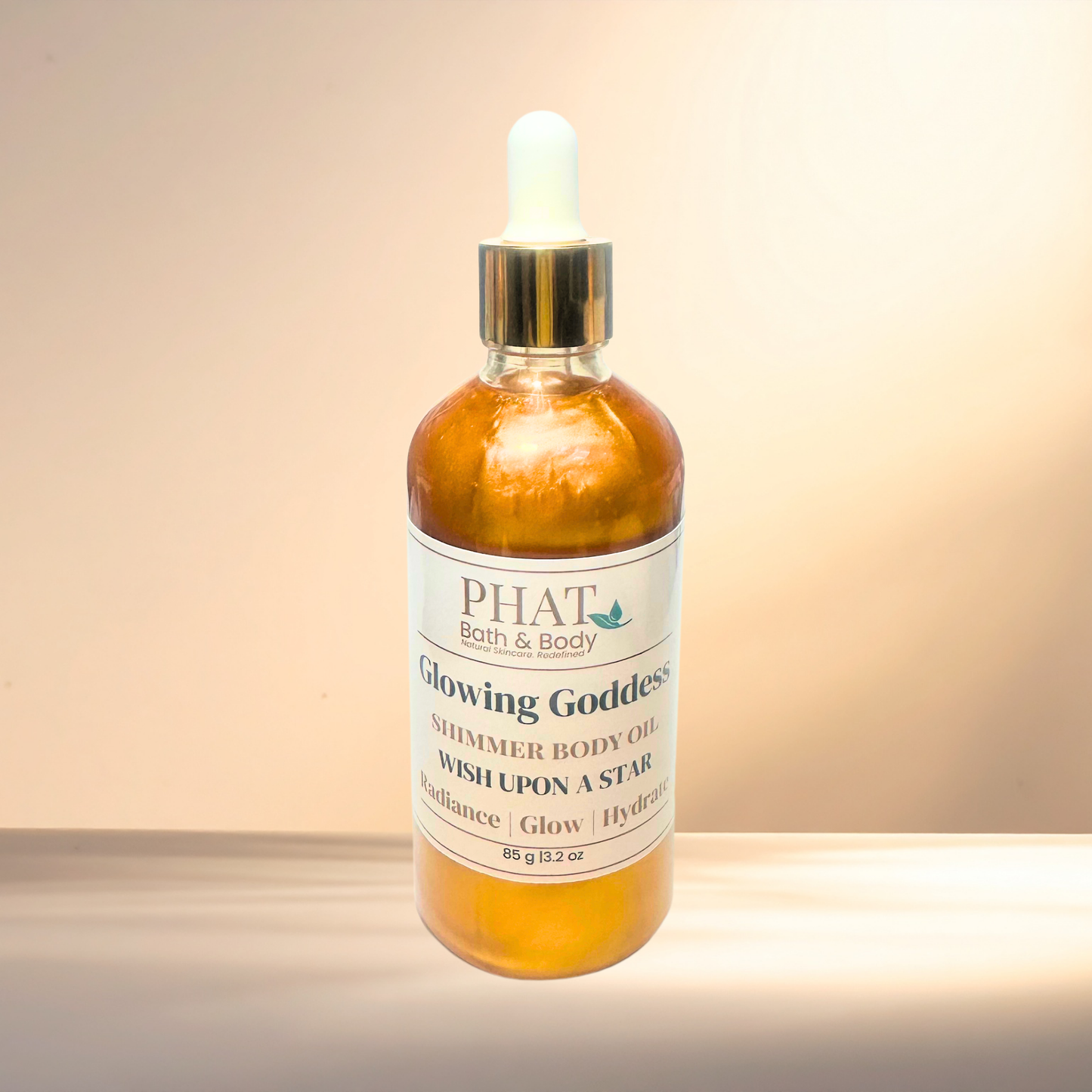 Bottle of PHAT Bath & Body Glowing Goddess Shimmer Body Oil on a gradient background