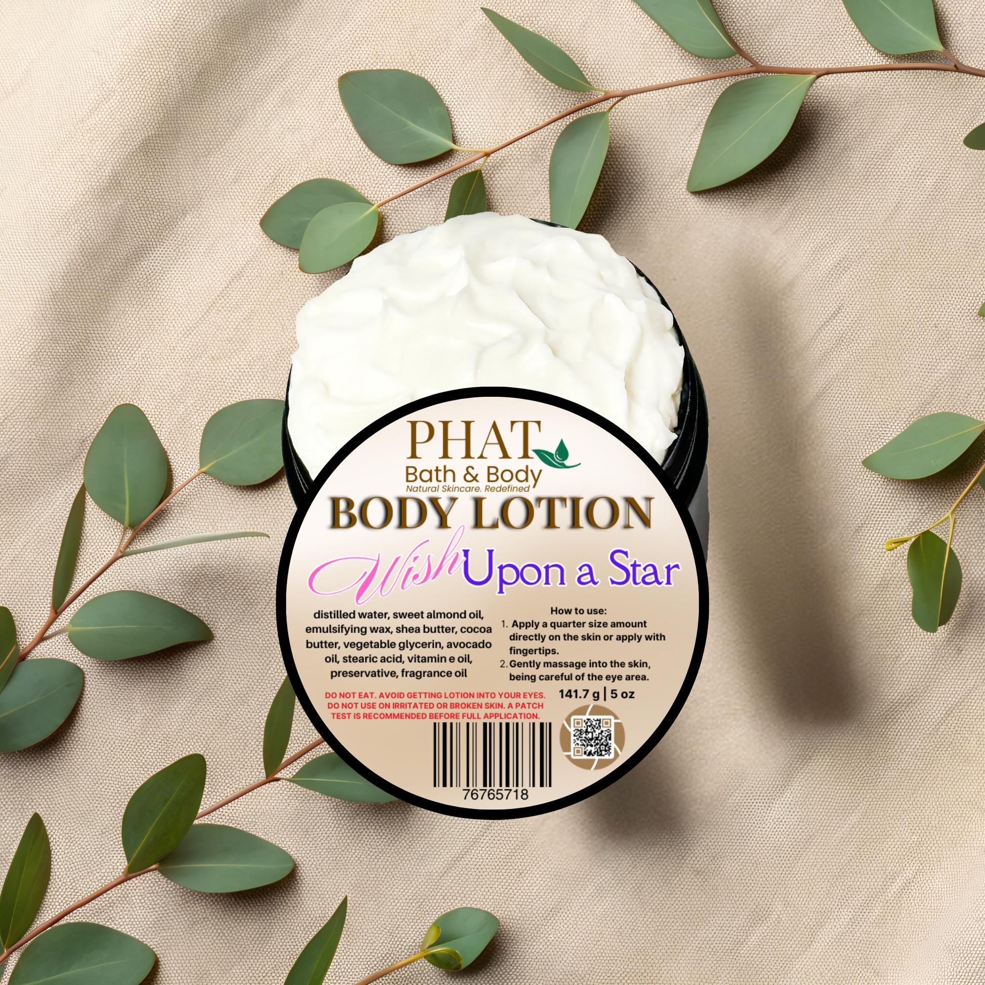 Body lotion container with 'PHAT Bath & Body' branding on a beige fabric background with green leaves.