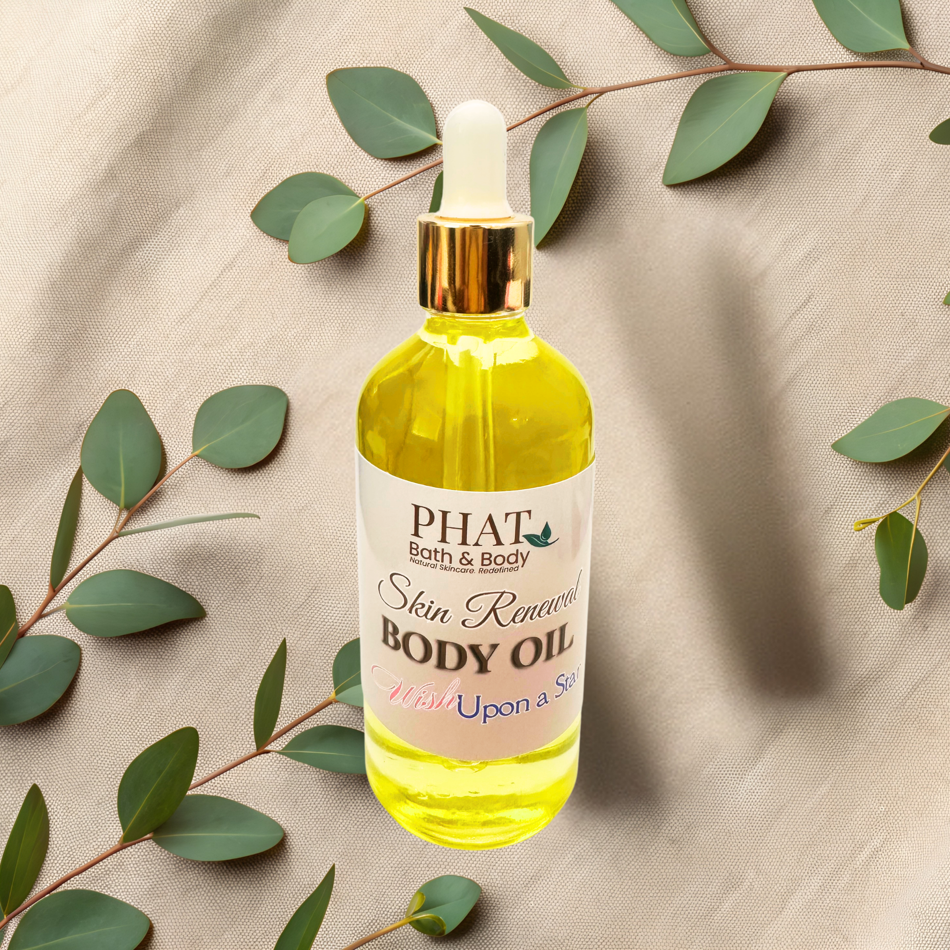 Bottle of PHAT Bath & Body Skin Renewal Body Oil with green leaves on a beige fabric background